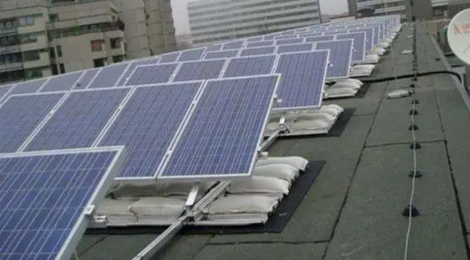 Plat dak met zonnepanelen op een open montagesysteem met PAC zandzakken eronder als ballast