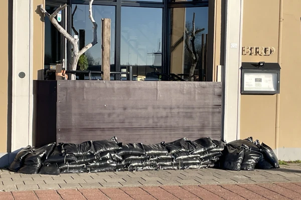Zandzakken uit een noodpakket opgestapeld bij een grote deur