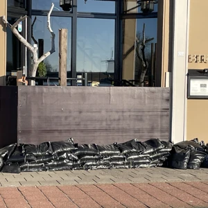 Zandzakken uit een noodpakket opgestapeld bij een grote deur